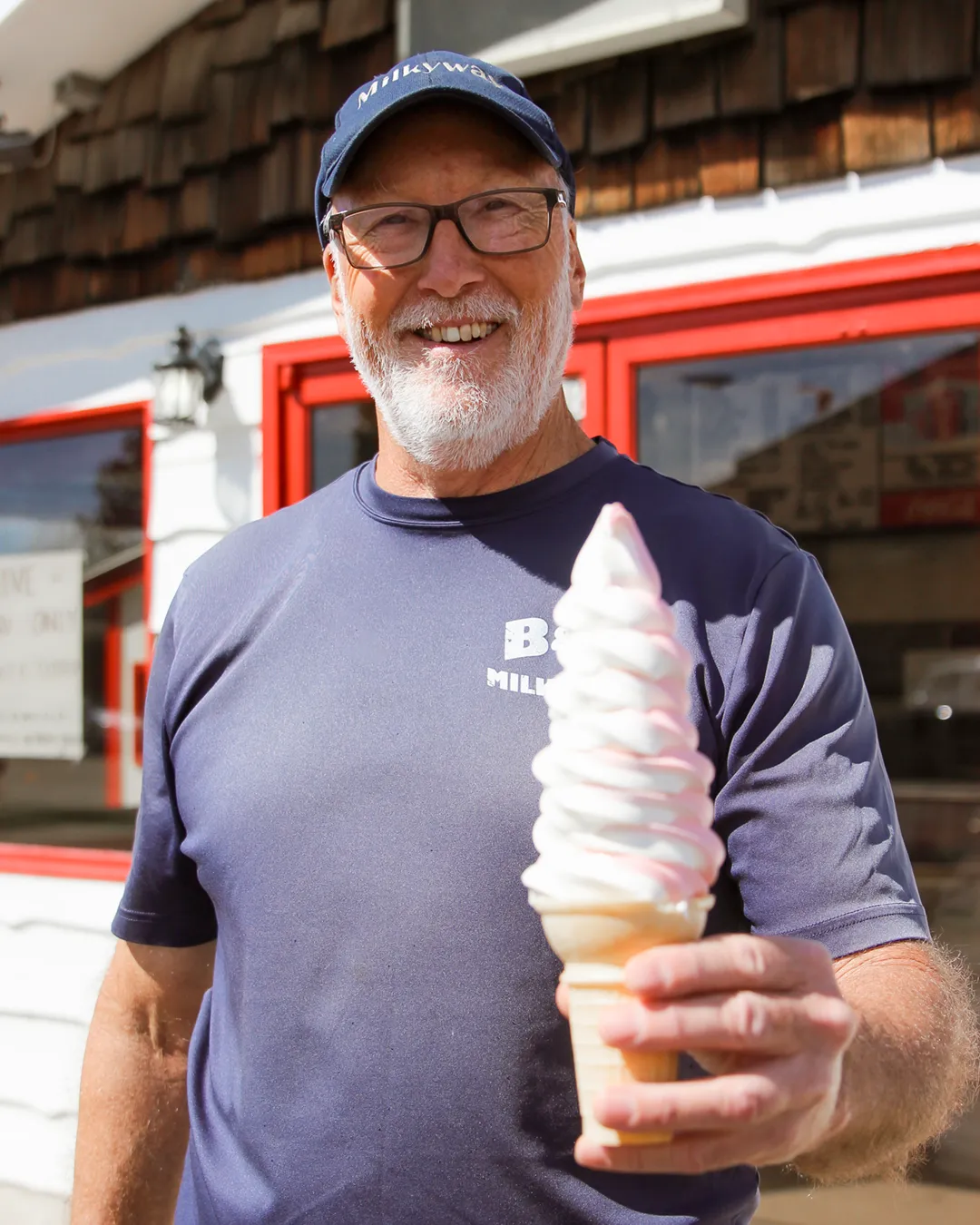 B & G Milkyway owner, Bruce Bettmeng holding an ice cream cone that features our original strawberry soft serve.